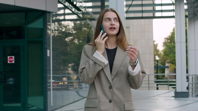 portrait of a business woman talking on the phone. brunette woman walks outside near the business center where she works. the concept of a business woman satisfied with her job