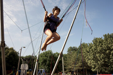 teenage girl jumping in a trampoline with security ropes 