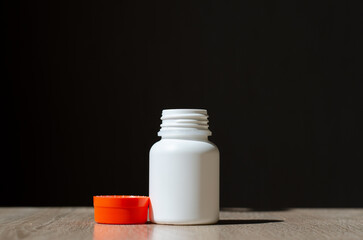 Plastic jar for pills. Cream container. White jar with orange lid. The sterile container stands on the table.