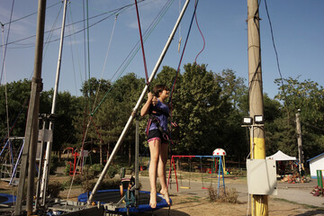 teenage girl jumping in a trampoline with security ropes 