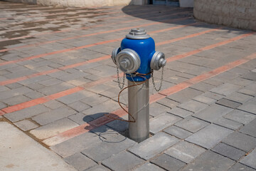 Close-up of a metal hydrant dug into the ground in the city for firefighters. Tools for preventing...