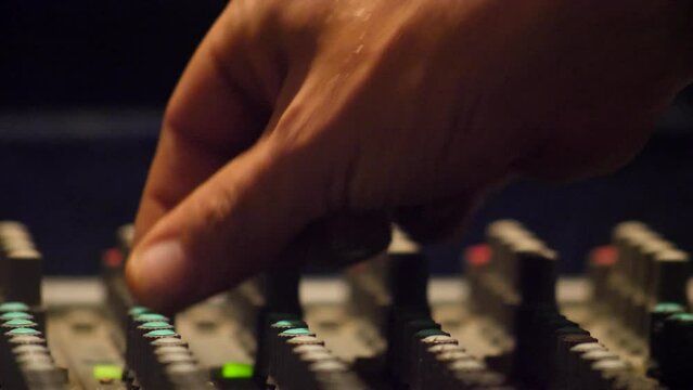 Close shot of fingers turning button on recording studio mixing console