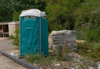 A plastic outdoor toilet of green color on the territory of the construction site for the use of a...