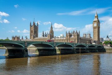 Red buses on Westminster bridge over river Thames, Big Ben and the houses of parliament in London,...