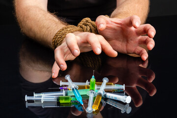 Close-up bound male hands craving for syringes filled with drugs. Drug addiction dependence and...