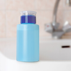 Blue plastic bottle with beauty liquid in the bathroom background