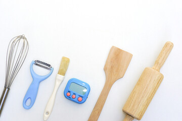 Top view kitchenware wooden rolling pin, wooden spatula and egg beater on white background.