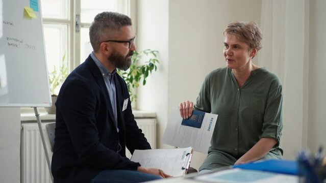 Man volunteer helping Ukrainian woman to fill in forms at asylum centre.