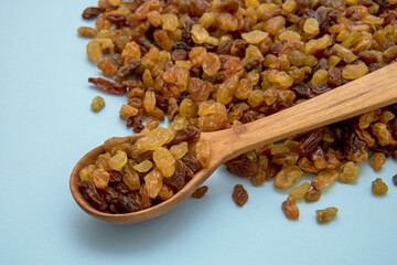 wooden spoon with raisins on a blue background, culinary background