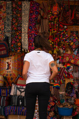 Obraz na płótnie Canvas Young woman with her back turned looking at the colorful products inside the new handicraft market in Pisac, Peru. 