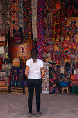 Young woman with her back turned looking at the colorful products inside the new handicraft market...