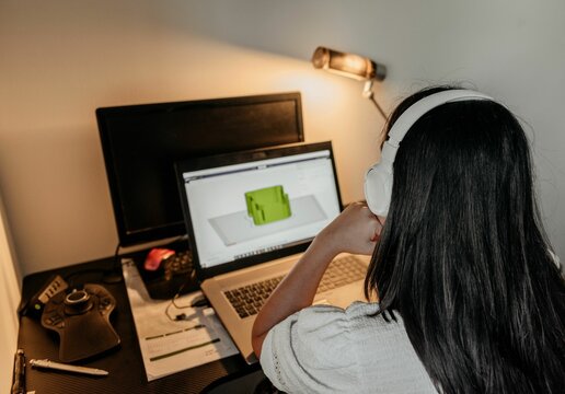 Female From Behind Sitting At Her Desk And Working On Her Laptop