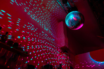Large disco ball reflecting the light of cherry color in a dark hall for discos. Disco symbol. Copy...