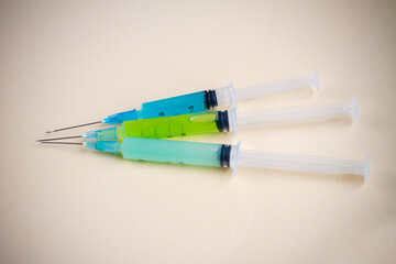 Close-up three colorful filled syringes on beige background. Drug use or vaccination concept.