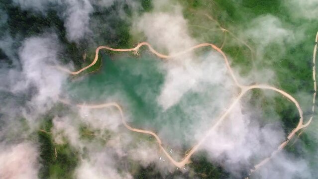 Mountain, forest lake on Karagol Plateau, Tarakli Village in Sakarya, Turkey. White clouds rolling over beautiful mountain lake surrounded with pine trees. Drone aerial top down view. 
