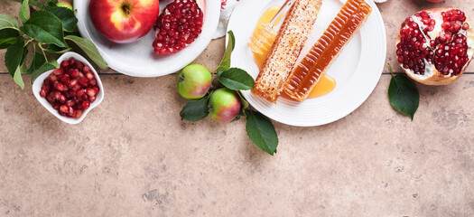 Rosh Hashanah. Honey jar, honeycomb, apple and pomegranate on light beige old rustic concrete...