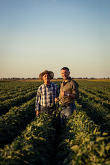 Portrait of two farmers in a field examining soy crop at sunset. © Zoran Zeremski