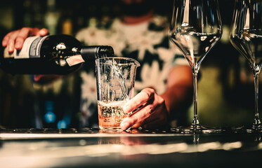 bartender pouring white wine into a glass in cafe or bar