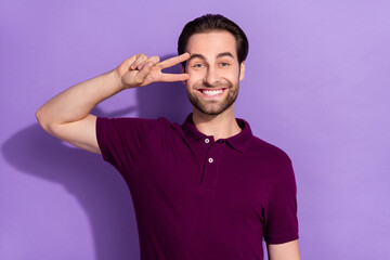Photo of cute funky cheerful male showing v-sign on eye playful mood fool around isolated on violet color background
