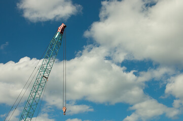 boom tower crane, pictured construction crane on the background of blue sky and clouds