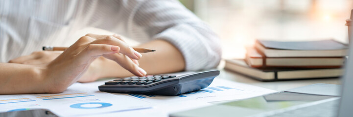 crop shot of business woman checks her work and uses a calculator to calculate her annual financial...