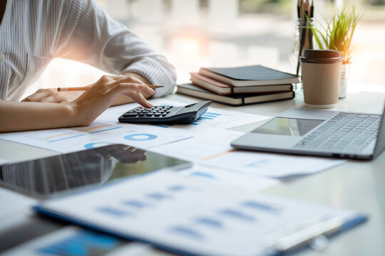 crop shot of business woman checks her work and uses a calculator to calculate her annual financial statements. Turnover and Profit Balance Sheet Making financial records in paper audits.