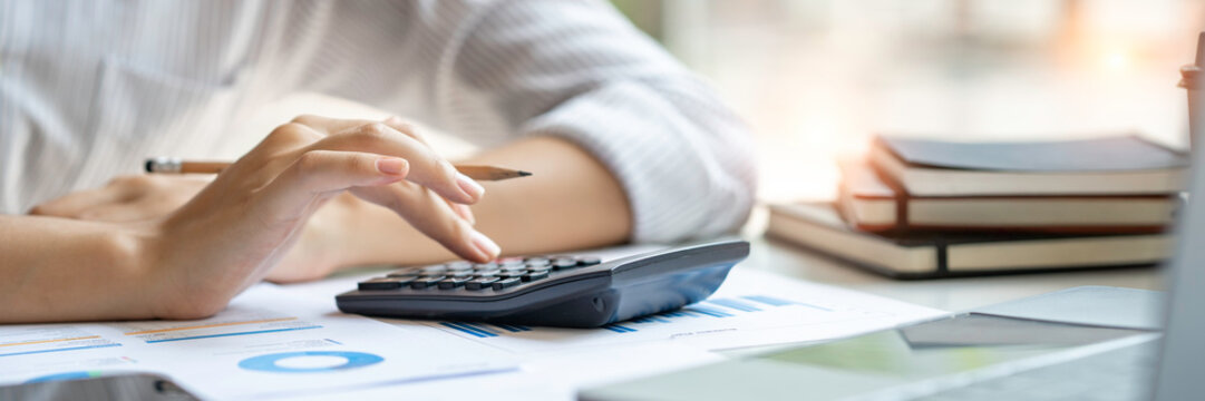 crop shot of business woman checks her work and uses a calculator to calculate her annual financial statements. Turnover and Profit Balance Sheet Making financial records in paper audits.