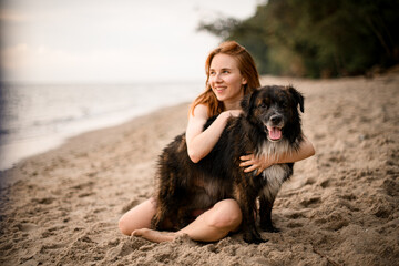 view of dog on the beach being hugged by young woman