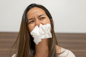 Woman sneezing in tissue at home.