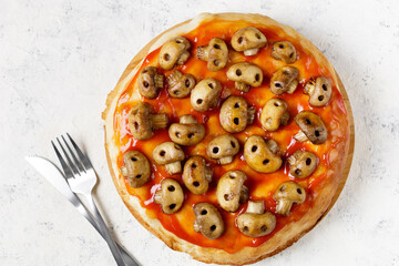 Homemade pizza with tomato sauce and mushrooms in the form of skulls. Concept for Halloween celebrations