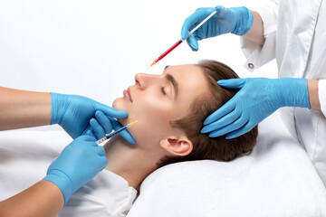 Men's cosmetology. Beautician makes a man a rejuvenation injection procedure of a handsome young man in a beauty salon.