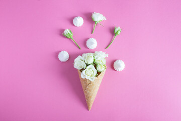 Ice cream cone with white roses and meringue the pink background. Top view. Close-up. Copy space.