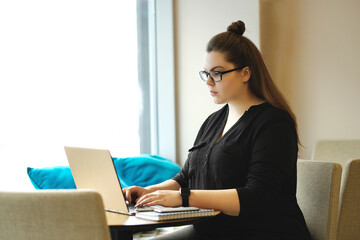 A freelance worker taps away on a laptop in a bustling cafe, blending work and leisure in a stylish and modern setting.