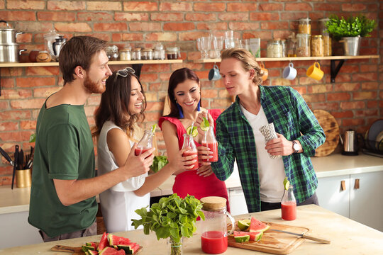 Get the party started with this fun and vibrant stock photo of a group of people enjoying food and drinks in the kitchen.