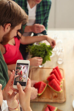 Get the party started with this fun and vibrant stock photo of a group of people enjoying food and drinks in the kitchen.