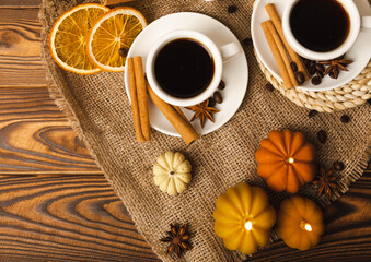 Candles in the form of pumpkins with fragrant coffee on a background of spicy spices of star anise and cinnamon on a brown wooden background.Cozy home decor.Halloween concept.Happy Thanksgiving.