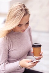 This multitasking and stylish blonde model effortlessly balances work and pleasure, striking various poses with a coffee in hand