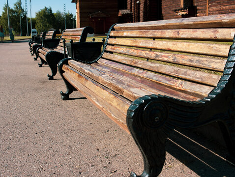 A bench made of metal and wood stands in the park