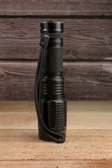 Vertical shot of a black technical torch light on a wooden surface