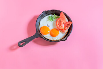 Healthy breakfast food fried egg in skillet pan on pink table.