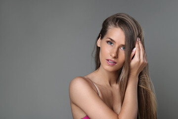 Sensual Simplicity: Beautiful Woman Poses in Lingerie Against a Grey Studio Background, Exuding Confidence and Elegance