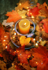 autumnal leaves, cones, acorns and candle in glass lantern on abstract background. fall season....