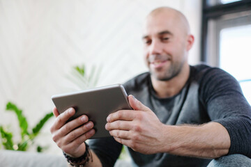 Man at home watching on tablet and smiling