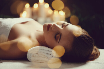 Beautiful young woman relaxing in spa salon and blurred bokeh effect background