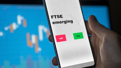 Un investisseur analyse le fonds ETF émergent FTSE à l'écran. Un téléphone affiche les prix de l'ETF Londres Angleterre Londres ftse Angleterre pour investir, texte en anglais.