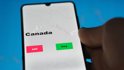 Naklejka premium Un investisseur analyse le fonds FNB Canada à l'écran. Un téléphone affiche les prix de l'ETF canadien canada canadien à investir, texte en anglais.