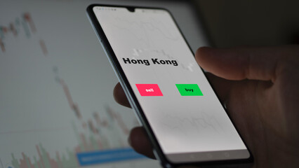 An investor's analyzing the Hong Kong etf fund on screen. A phone shows the ETF's prices Hongkonger hong kong to invest