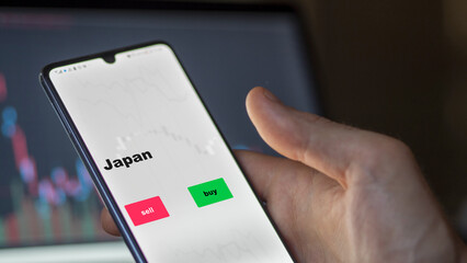 An investor's analyzing the Japan etf fund on screen. A phone shows the ETF's prices Japanese japan japanese to invest