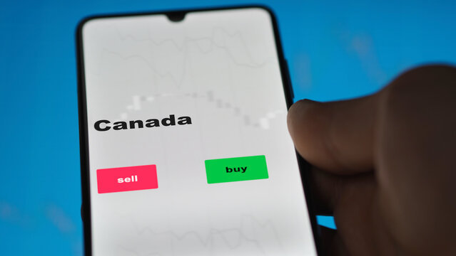 An Investor's Analyzing The Canada Etf Fund On Screen. A Phone Shows The ETF's Prices Canadian Canada Canadian To Invest