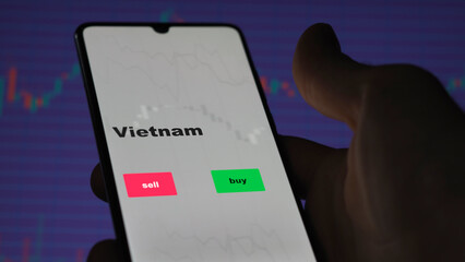 An investor's analyzing the Vietnam etf fund on screen. A phone shows the ETF's prices Vietnamese to invest